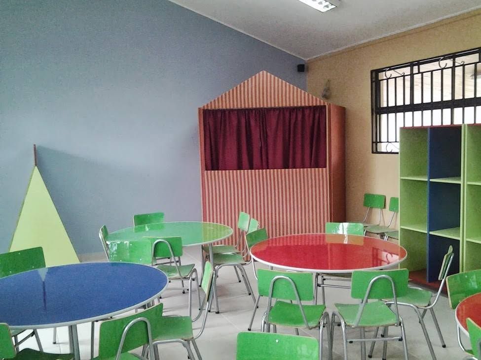 Aula con mesas redondas de colores y un teatro de títeres